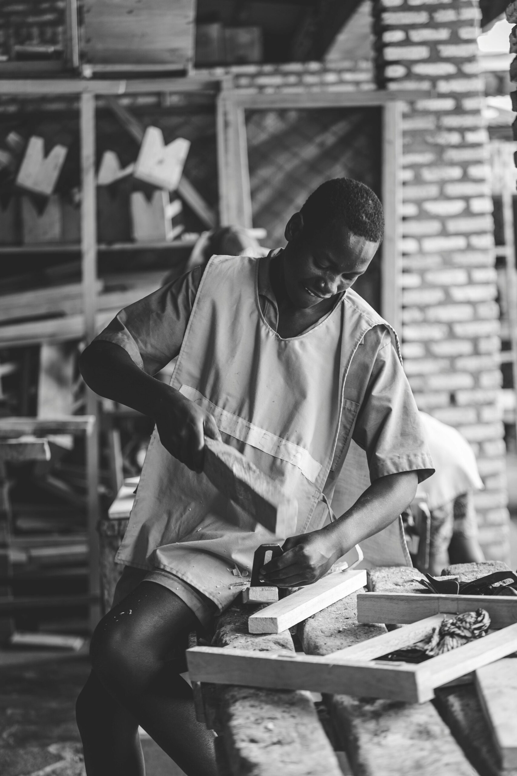 Black and white image of a carpenter concentrating on woodworking in a workshop.